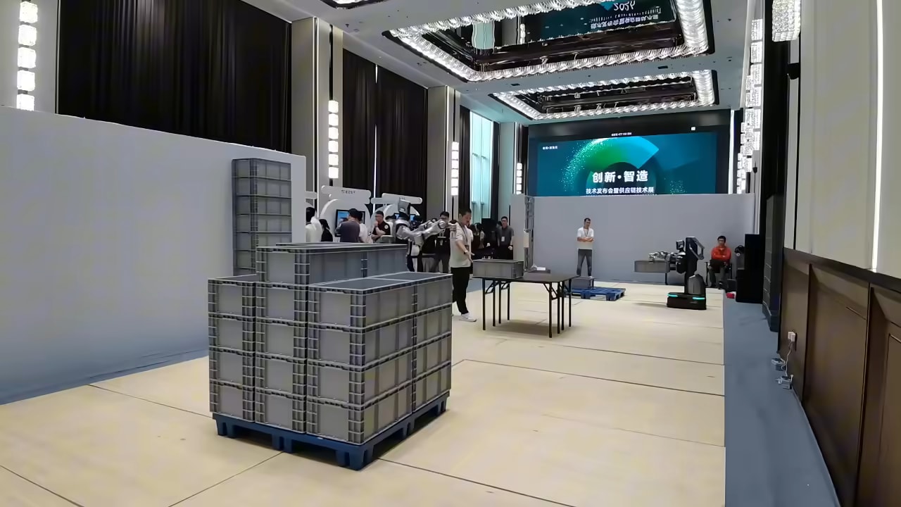 Robot Cruzr Y1 med delom med zloženimi paletami v predstavitveni dvorani, posnetek proizvajalca UBTECH