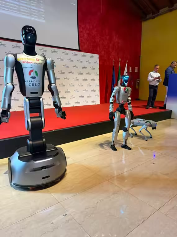 Humanoidna robota CRUZ in NEO ter robotski pes pred odrom na dogodku Confartigianato