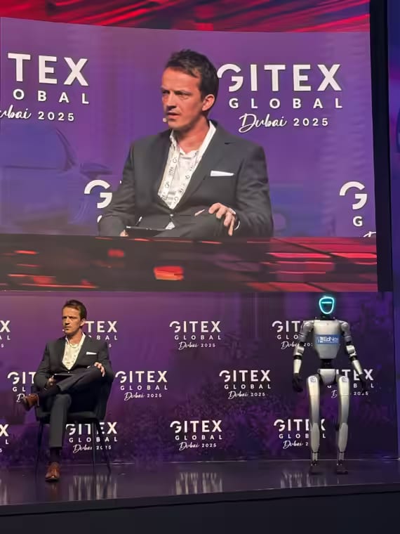Humanoidni robot na odru konference GITEX Global v Dubaju, ob njem sedi govorec