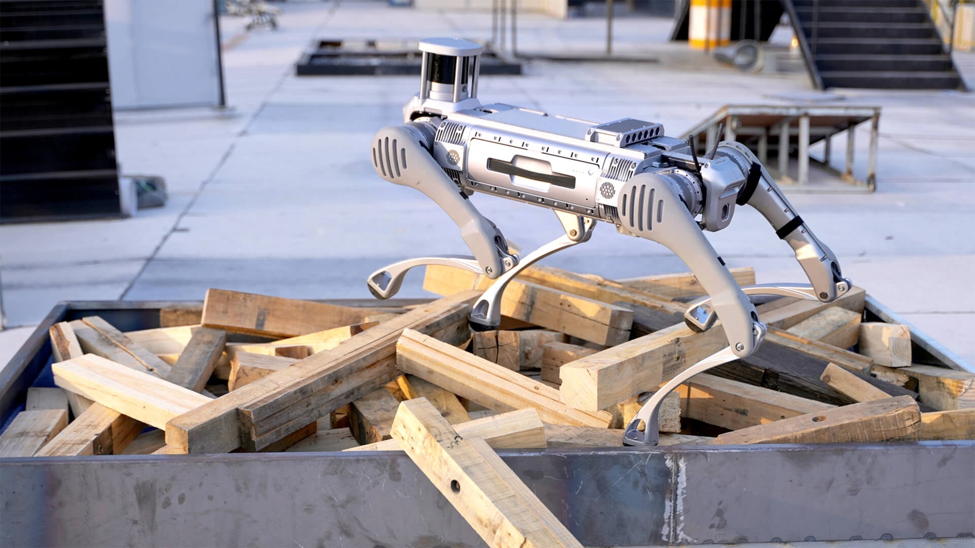 Robot B2 stopa čez kup neurejenih lesenih tramov