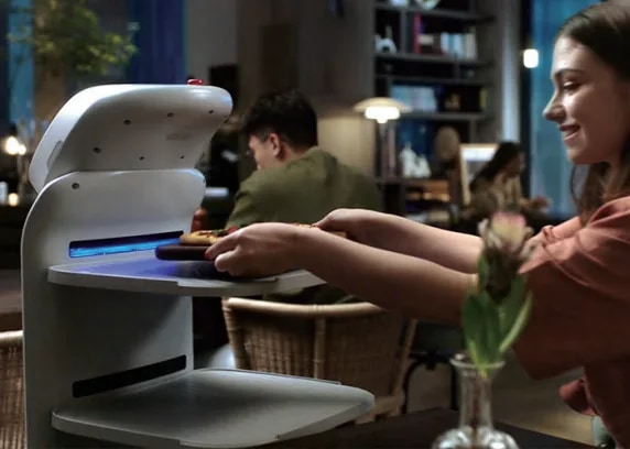 Gost vzame krožnik s pladnja robota CADEBOT za mizo v restavraciji