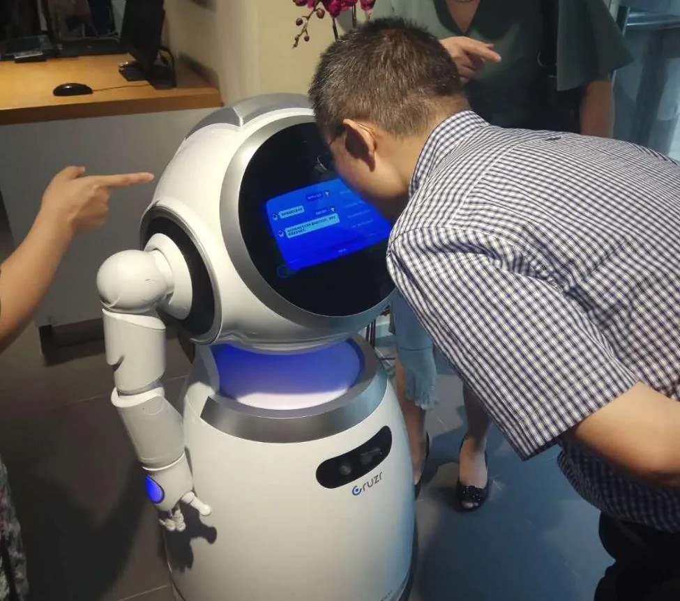 Obiskovalec se dotakne zaslona robota Cruzr in bere odgovor